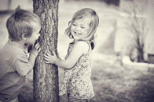 Фото Девочка с мальчик прячутся за деревом