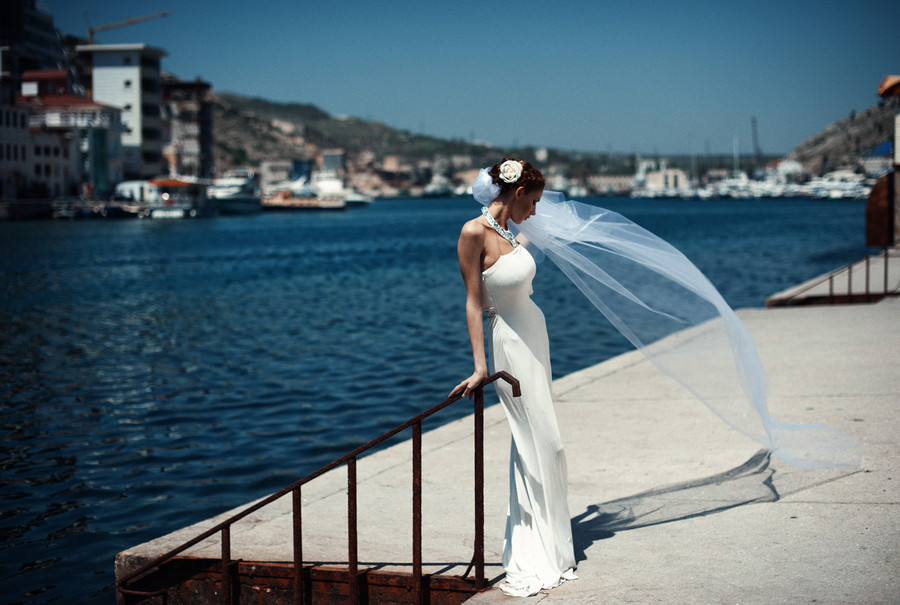 Фото Девушка в свадебном платье стоит у воды глядя в сторону