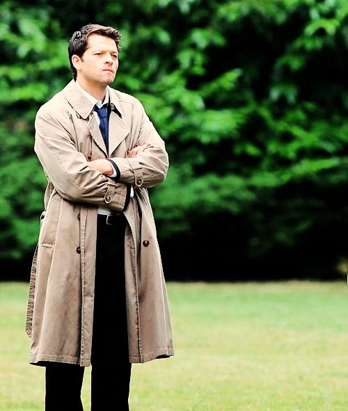 Фото Миша Коллинз (Misha Collins) в роли ангела Кастиэля (Castiel), стоячего на газоне, сложив руки на груди - сериал 'Сверхъестественное / Supernatural'