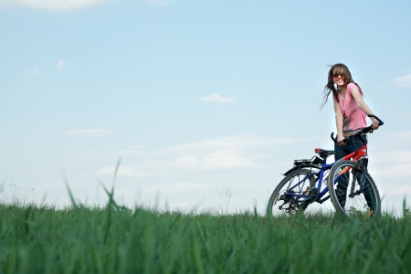 Фото Девушка с велосипедом на зеленой поляне