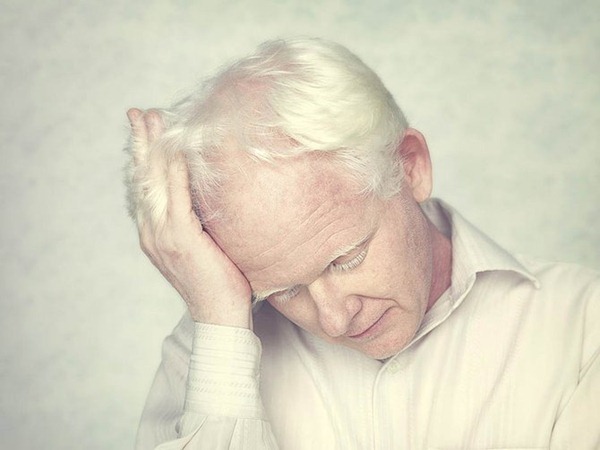 Фото Мужчина альбинос держится рукой за голову