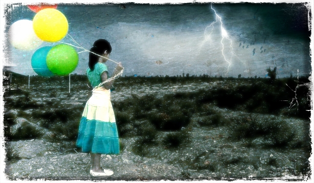 Фото Девушка с разноцветными шариками стоит в поле под дождём глядя вдаль