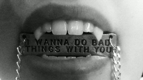Фото Табличка с цепочкой в вампирских клыках 'I wanna do bad things with you / Я хочу сделать плохие вещи с тобою'
