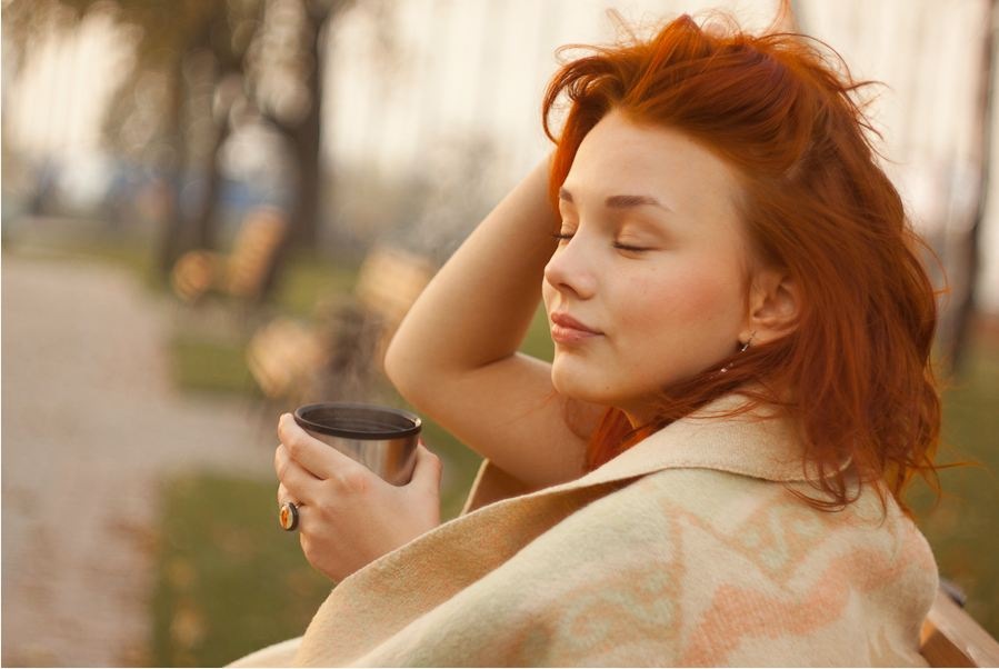 Фото Рыжая девушка укрытая одеялом пьет чай