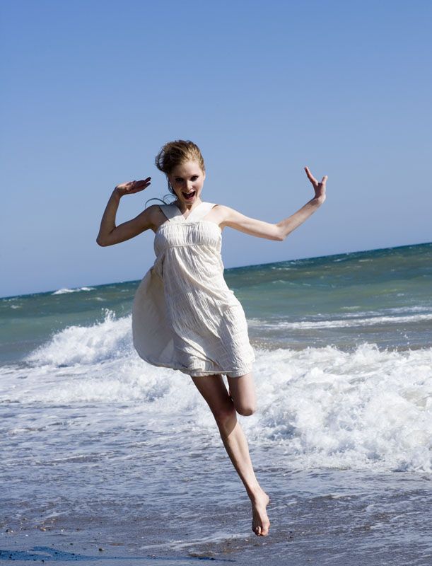 Фото Девушка убегает от морской волны в белом платье