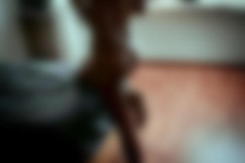 Фото Девушка с голой попой и браслетом на руке стоит посреди комнаты, опустив одно колено на кровать, фотограф Джоэль Сосса / Joel Sossa