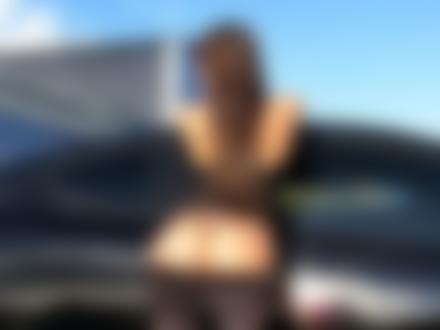 Фото Девушка в топике приспустила штаны возле черной машины