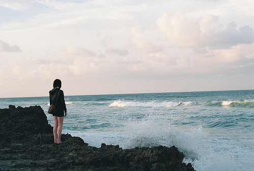 Фото Девушка стоит на берегу и наблюдает за бушующим морем