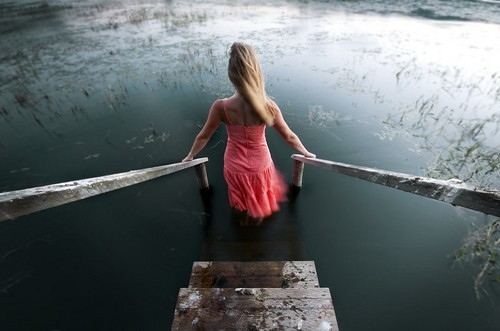 Фото Девушка спускается по лестнице в темную воду