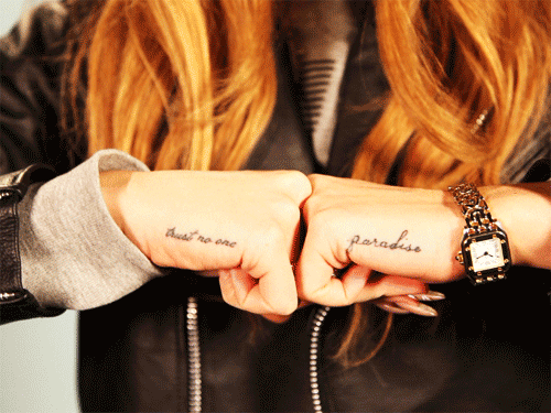 Фото Девушка сложила руки вместе, на них тату (Trust no one / Никому не доверяй, paradise / Рай), певица Лана Дель Рей /  Lana Del Rey
