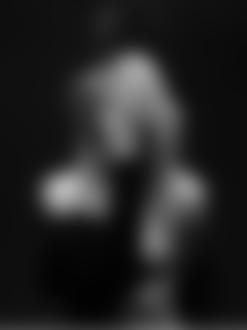 Фото Девушка ,с прикрывшим волосами лицом и полуспущенным пиджаком,поднесла сигарету ко рту и курит