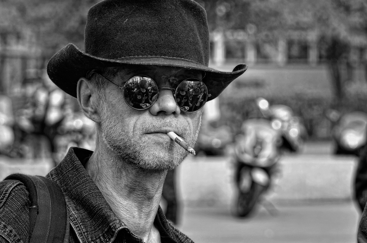 Фото Мужчина в очках и шляпе, с сигаретой во рту