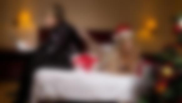 Фото Девушка, лежащая в нижнем белье и шапочке снегурочки на кровати, грустно смотрит на украшенную новогоднюю елку, ее парень увлеченно смотрит в лежащий у него на коленях ноутбук