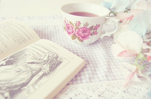 Фото Раскрытая книга на столе, возле чашки с чаем