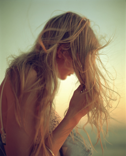 Фото Девушка с распущенными светлыми волосами, растрепавшимися от ветра, на фоне неба