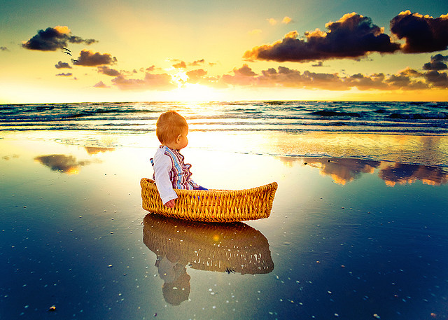 Фото Малыш сидит в корзинке на берегу моря смотря куда-то