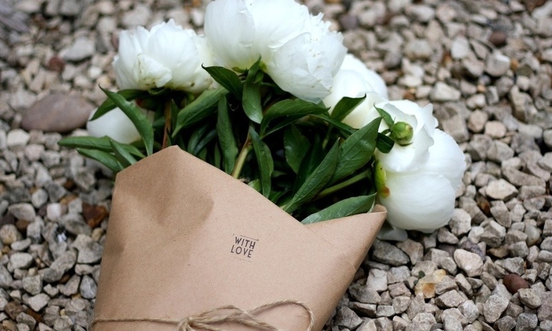 Фото Букет красивых белых пионов, лежащих в бумажном кульке на гальке, с надписью 'WITH LOVE' / 'C любовью'