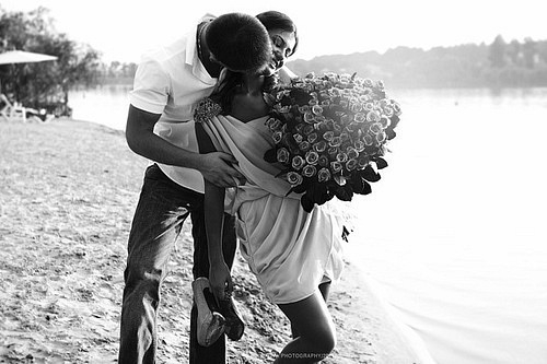 Фото Девушка с букетом цветов в руках парень целует ее в шею