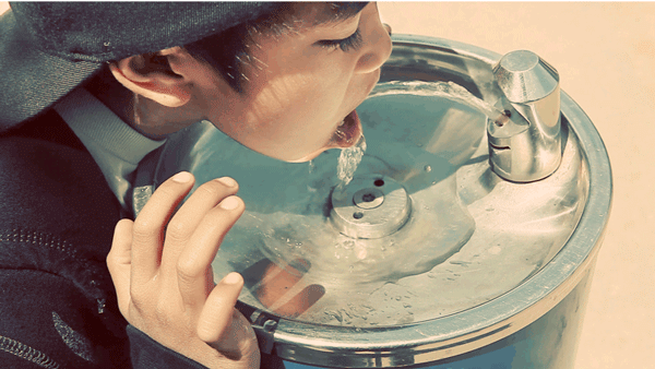 Фото Мальчик азиатской внешности пьет воду из уличного фонтанчика