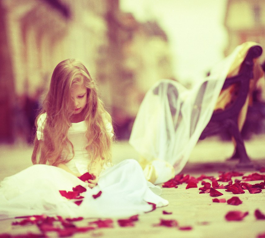 Фото Девочка в белом платье сидит на полу в красных лепестках роз