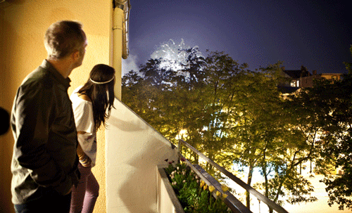 Фото Парень и девушка с лоджии наблюдают за огненными вспышками  в ночном небе
