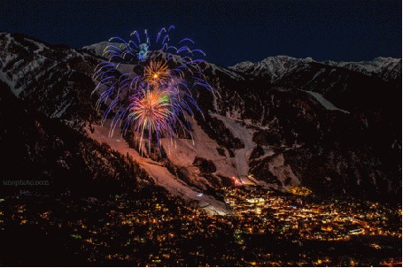 Фото Фейерверк в ночном небе города, стоящего в предгорье снежных вершин