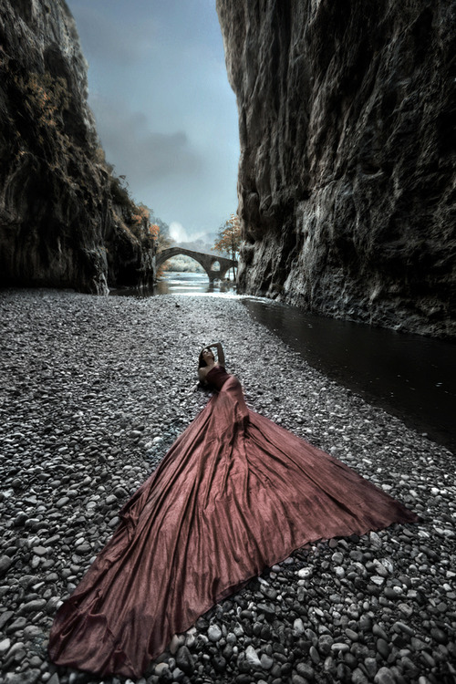 Фото Девушка в шикарном платье лежит на камнях  у воды