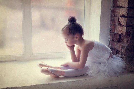 Фото Девочка балерина сидит на подоконнике у окна, подперев голову рукой