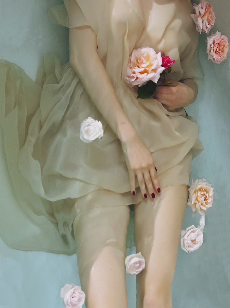 Фото Девушка в светлом платье лежит в воде и держит розу