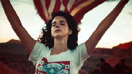 Фото Певица Лана Дель Рей / Lana Del Rey с закрытыми глазами держит американский флаг, который раздувается по ветру