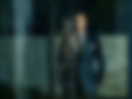Фото Мужчина стоит черно-белом костюме в полоску у стекла, в котором отражается обнаженная девушка