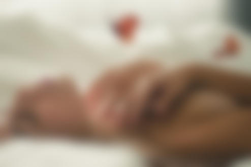 Фото Девушка лежит на постели, положив руки на грудь, над ней летают бабочки