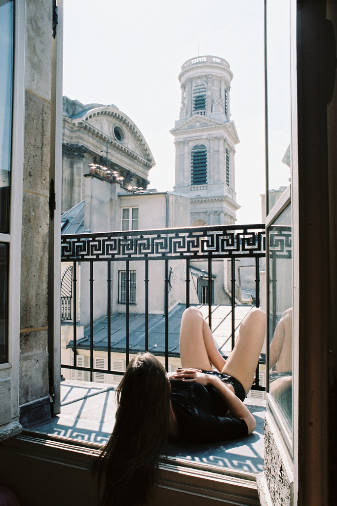 Фото Девушка лежит на балконе, смотря на красивый собор