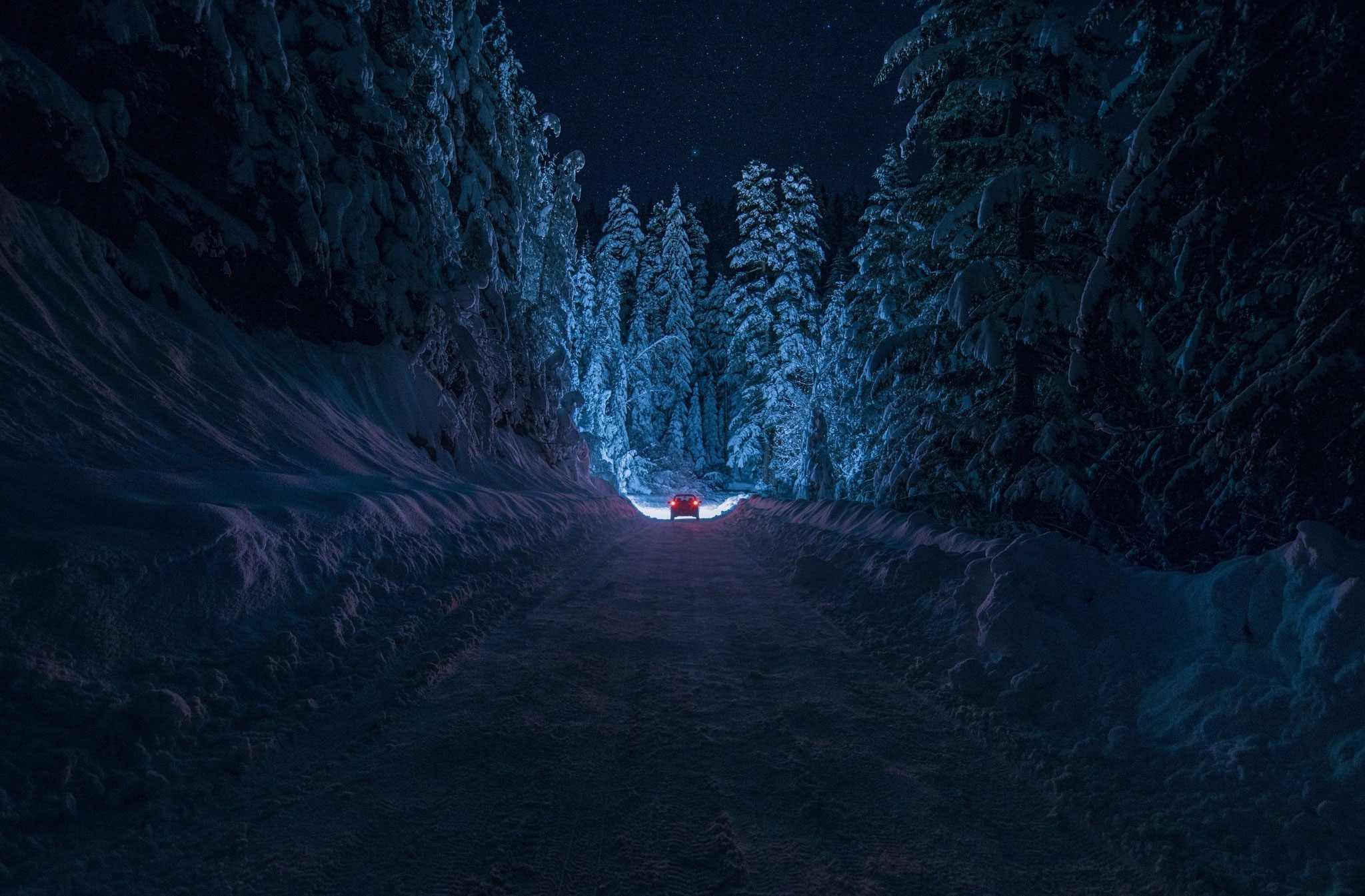 Зимняя заснеженная дорога в лесу, с удаляющимся автомобилем
