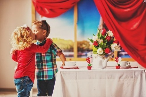 Фото Девочка с мальчиком целуются стоя у столика