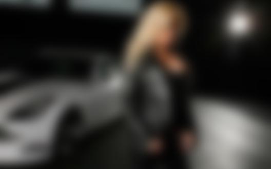 Фото Девушка блондинка в черной кожаной куртке стоит рядом с белой машиной
