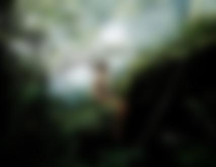 Фото Полуобнаженная девушка с копьем в руке сидит на краю обрыва