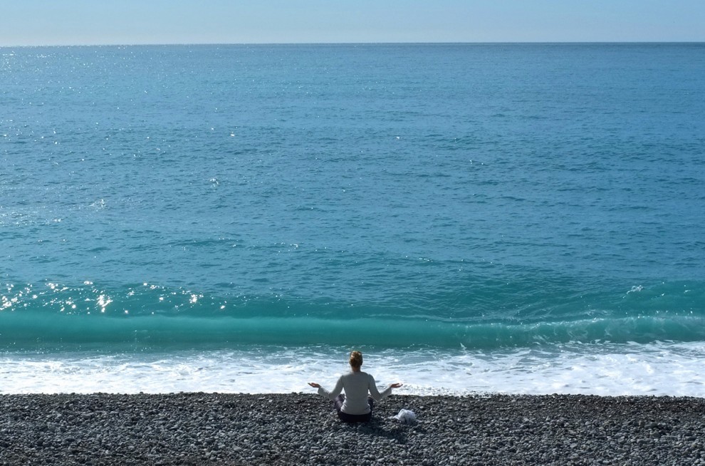 Фото Медитирующая женщина, сидящая на гальке морского берега, фотограф Lionel Cironneau