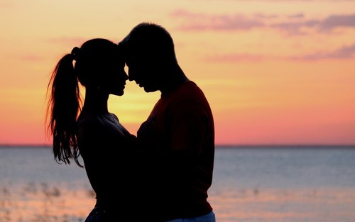Фото Девушка и мужчина смотрят друг на друга на фоне закатного неба