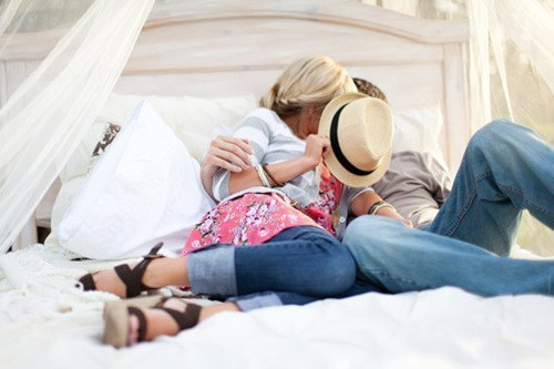 Фото Девушка с парнем лежат в одной кровати и целуются, прикрыв лица шляпой