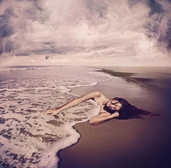 Фото Девушка спит на берегу моря, укрывшись волной