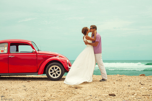Фото Целующаяся влюбленная пара, возле красной машины, на берегу моря
