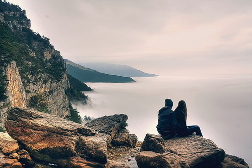Фото Мужчина и девушка, сидя на скале, любуются морем