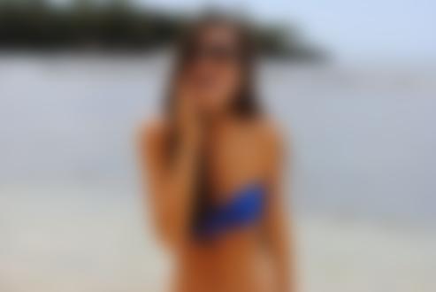 Фото Девушка в синем белье и очках, стоит у моря улыбаясь