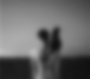 Фото Девушка связана косой с хвостом черной кошки, сидящей на ее плече на фоне крыши дома и неба, фотограф Noell S. Oszvald / Ноель С. Освальд
