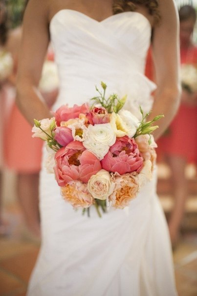 Фото Девушка в свадебном белом платье держит в руках букет из роз и пионов