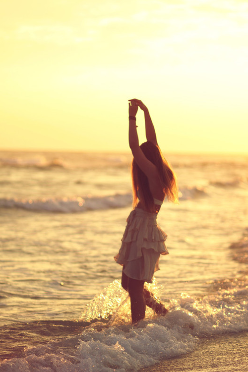 Фото Девушка на закате у моря вытянула руки вврх