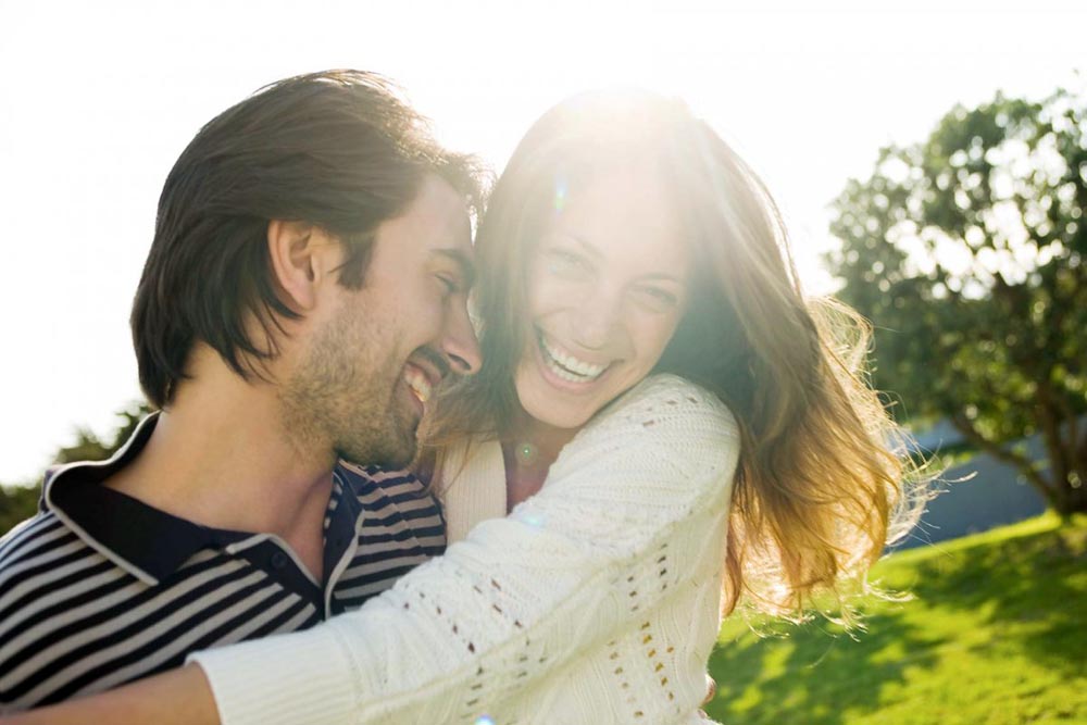 Фото Девушка с мужчиной счастливо улыбаются на фоне солнца и природы