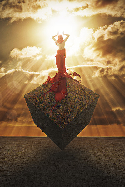 Фото Девушка в красном платке, переходящем в длинную юбку из краски, стоит на кубе и взывает молитвой к солнцу