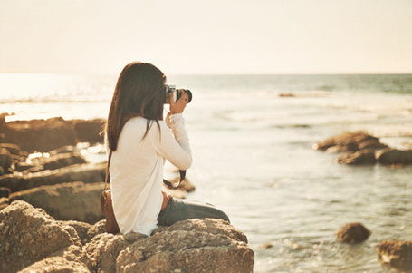 Девушка фотографируется на море.